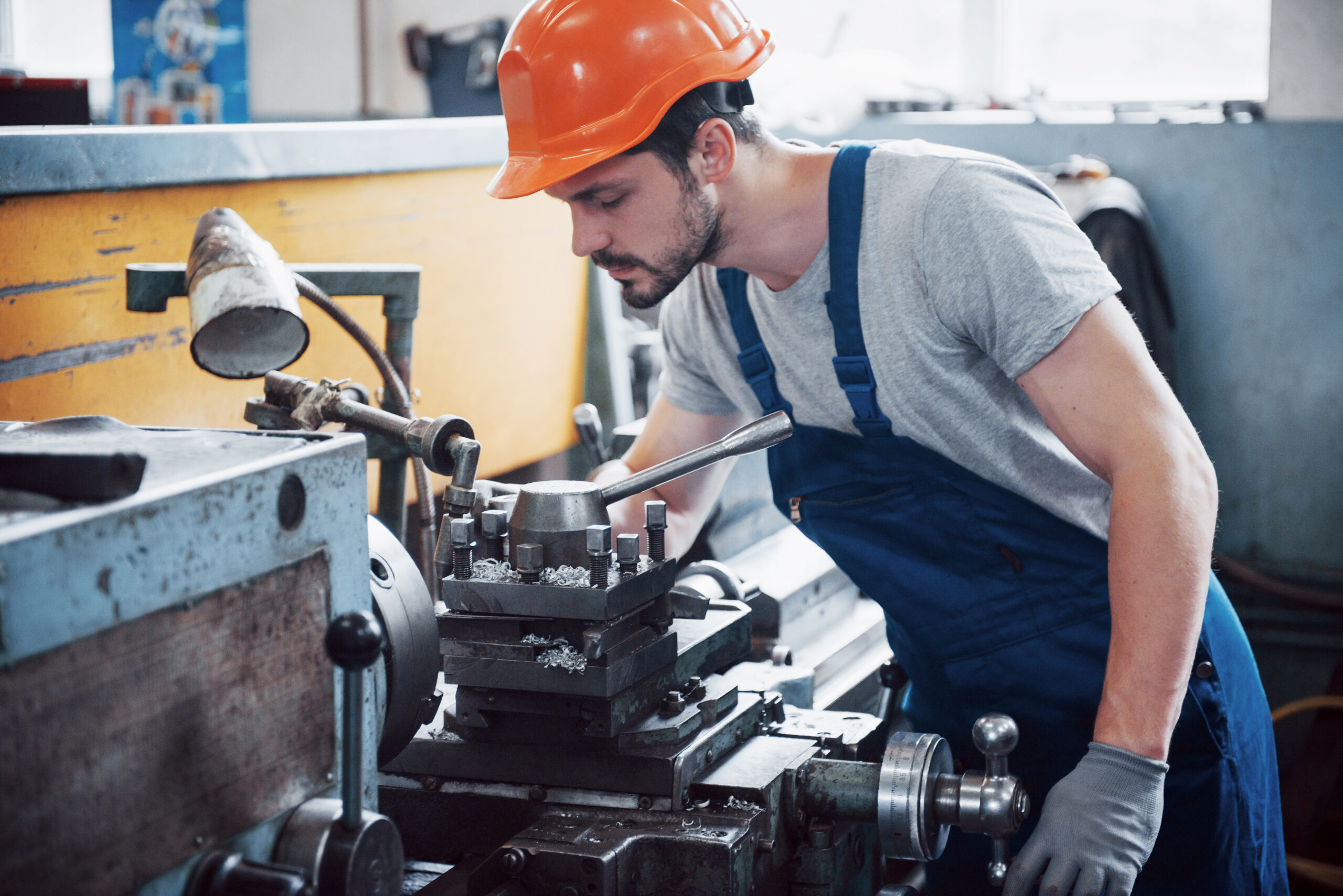 Portrait of a young worker in a hard hat at a large waste recycling factory. The engineer monitors the work of machines and other equipment.